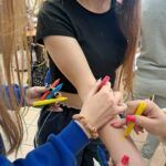 Przedstawicielki Samorządu Uczniowskiego rysują na ręce uczennicy kolorowe kwiaty